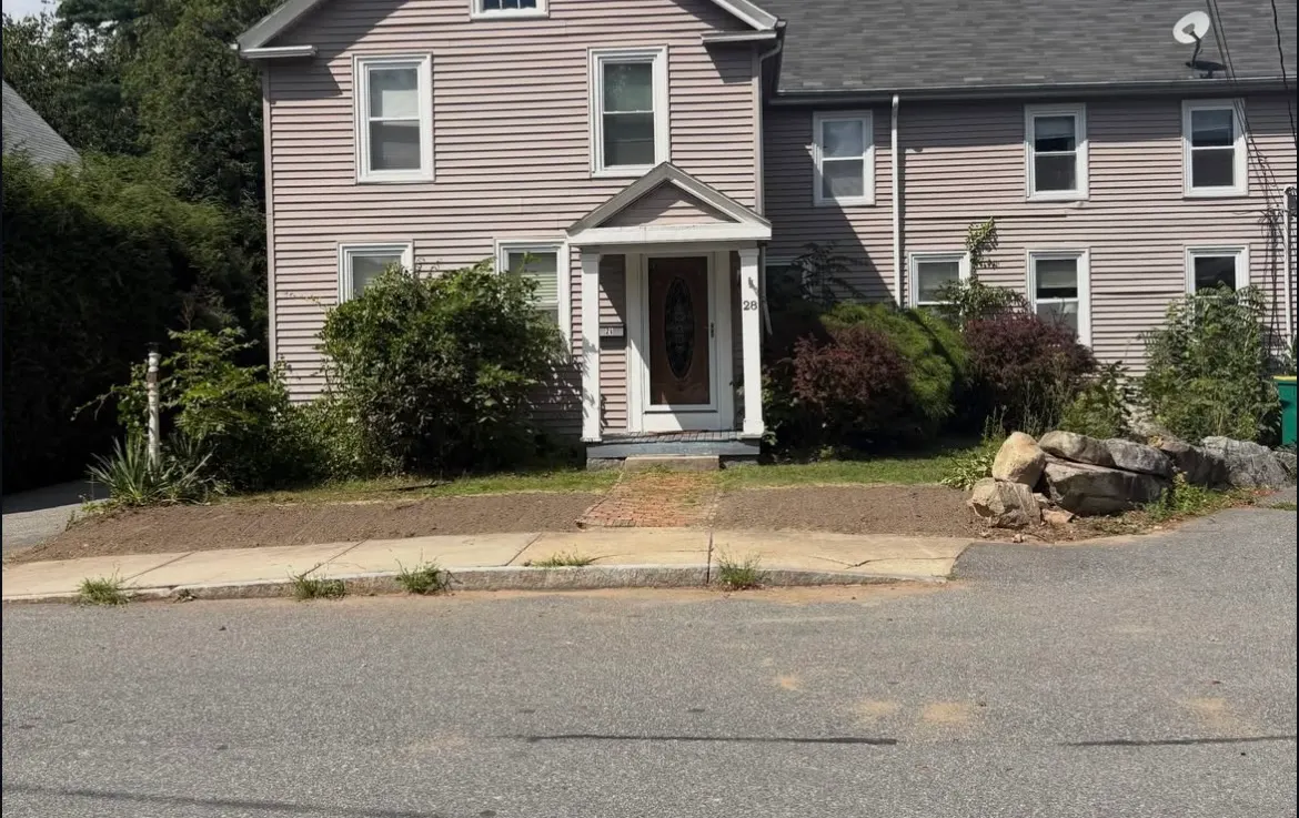After: shrubs cut back, front entrance and brick walkway cleared, beds raked clean